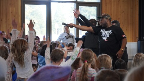 Local hip hop artist Brandon Greathouse, known as GR8, performs alongside a crowd of elementary school students during an Arts for the Schools assembly at Tahoe Expedition Academy