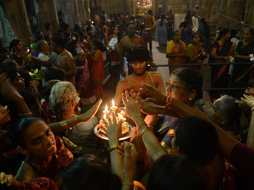 Sri Lankan Hindus receive blessings from a priest holding an oil lamp during the Maha Shivaratri festival at a temple in Colombo on March 10, 2013.