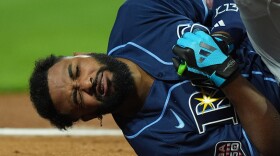 baseball player in blue tampa bay rays uniform hold his hand in pain 