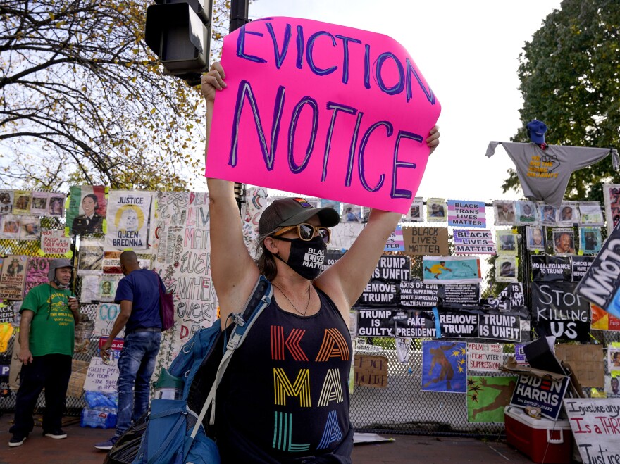 A protester holds up an eviction-related sign in Washington, D.C. The coronavirus rescue package just passed in Congress sets aside $25 billion for rental assistance and extends a CDC order aimed at preventing evictions.