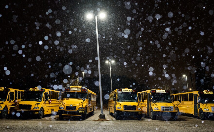 Snow falls on parked school busses in Raleigh.