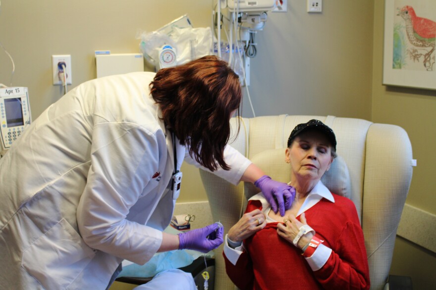 Anne Koller closes her eyes as an oncology nurse attaches a line for chemotherapy to a port in her chest. Koller typically spends three to six hours getting each treatment.