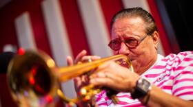 A man plays the trumpet in a red room.