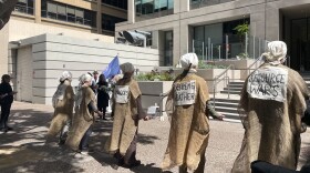 Activists gathered outside the steps of the San Francisco EPA Office donning all black, lab coats, and brown cloth labeled with signs warning of the impacts of climate change.