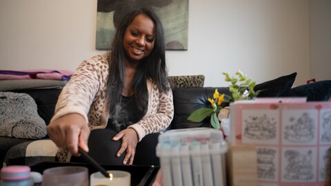 A woman in a sweater lights a candle.