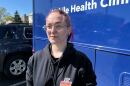 Harley Camryn poses outside of a blue mobile clinic at Planned Parenthood's Central West End location in St. Louis. They have pink hair, a black hoodie and glasses. 