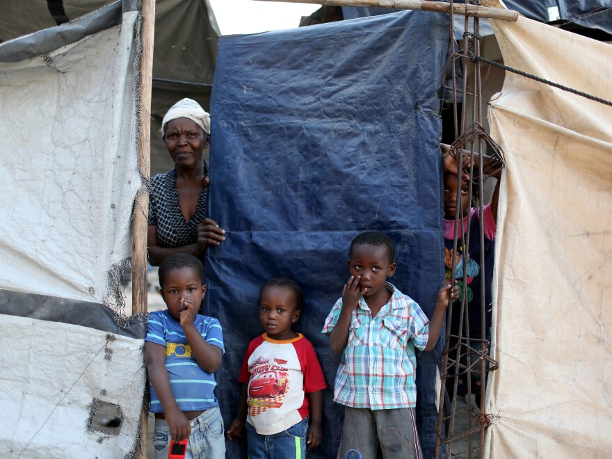 Members of a family look out from behind the tarp that serves as the front door to their home. The structure was built five years ago over the land where their home stood before the 2010 earthquake. At one point, about 1.5 million people lived in tents across Haiti. Now about 80,000 people live in these structures.