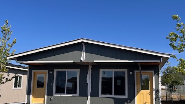 A single-story dark green duplex home with yellow doors. 