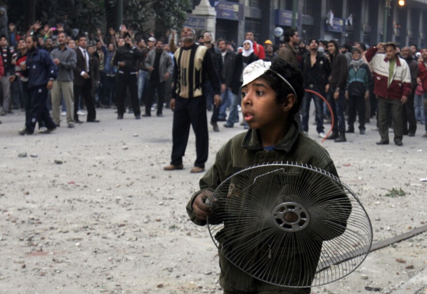 A youthful protester holds a fan cover to protect himself from rocks during clashes with military police near Tahrir Square in Cairo on Friday.