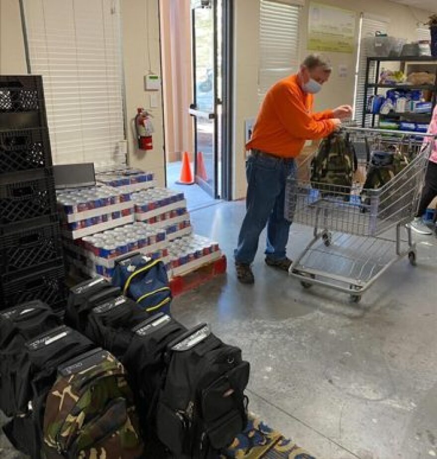 (Paul Gulig, a professor of molecular genetics and microbiology at the University of Florida and Catholic Charities board member, prepares full backpacks for delivery. “I just love this charity because look what we did,” Gulig said.“The work we just did, we know is going to be in some kid’s stomach this weekend.” Ashley Hearn/WUFT News)