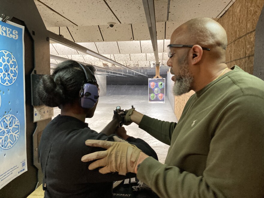 Sharis Lewis of Florissant, Missouri, tries her hand with a 12-gauge shotgun with the help of her husband, Russell.