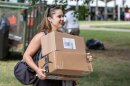 A female student carries boxes on campus.