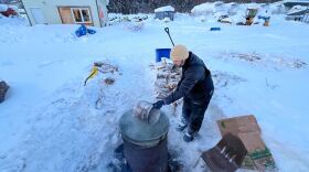 a musher gets hot water from a bucket