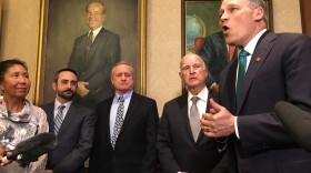 Gov. Jay Inslee speaks about climate change in the foyer of his office. On his right is former California Gov. Jerry Brown and state lawmakers