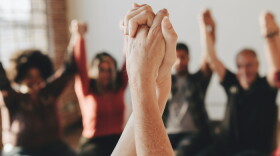 Group of diverse people holding hands up in the air