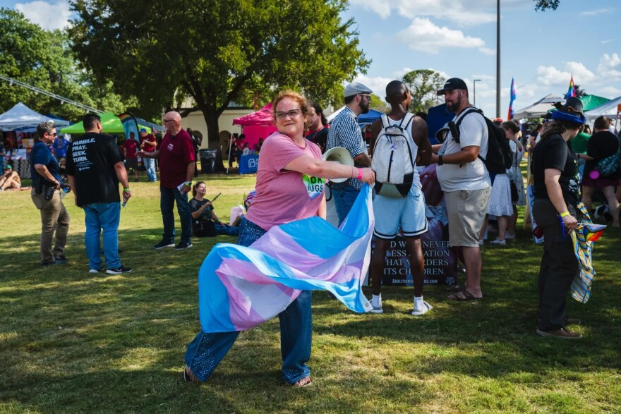 Holly Land dances with a trans pride flag to distract from protesters at Out on the Brazos on Oct. 18, 2025.