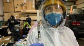 Dr. Shana Theobald holds up a dose of the COVID-19 vaccine.