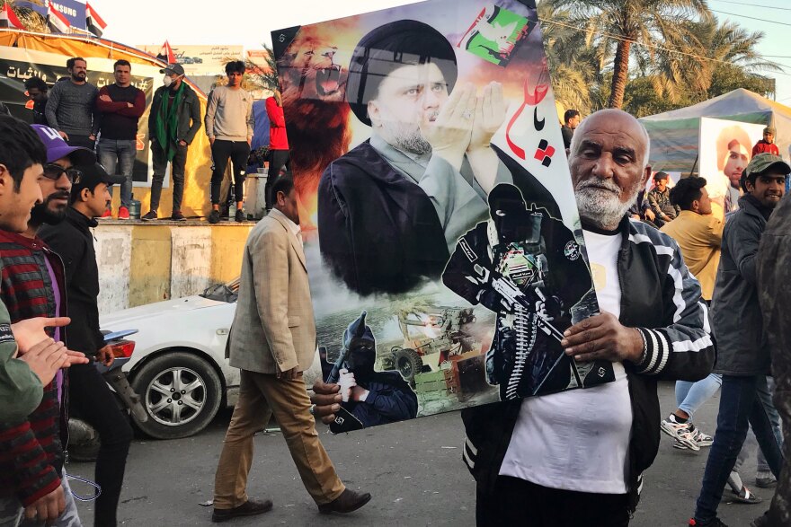 A Sadr follower in Tahrir Square holds a photo of the Shiite cleric along with some of his fighters. Sadr has called on followers not to carry his photo, but many do.
