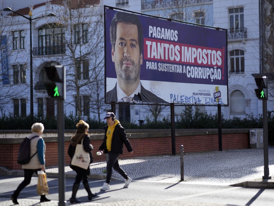 People walk by a billboard for Andre Ventura, leader of populist radical right party Chega (in English, Enough) with the words, "We pay so many taxes to sustain corruption", in Lisbon, March 4, 2024.