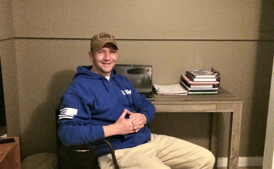 Veteran Travis Holt sits in the makeshift office he made in his spare bedroom.