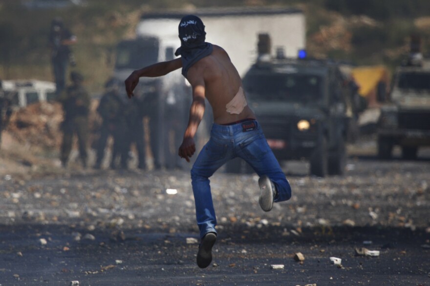 A masked Palestinian hurls a stone at Israeli troops during clashes outside the Ofer military prison, near the West Bank city of Ramallah on Tuesday, amid<em> nakba</em> demonstrations.