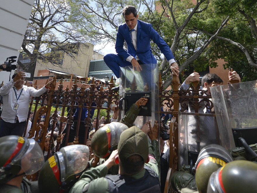 National Assembly President Juan Guaidó climbs the fence in a failed attempt to enter the compound of the legislature, as he and other opposition lawmakers are blocked from entering a session to elect new assembly leadership in Caracas, Venezuela, on Jan. 5.