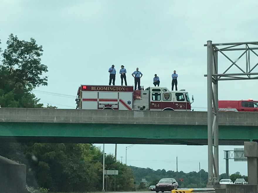 Bloomington fire fighters stand on an overpass of Ind. 45/46 Wednesday for the funeral procession of Owen County EMT Brandon Staley.