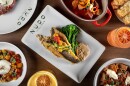 A filet of fish sits atop a bed of broccoli and sauce, surrounded by other Mediterranean dishes.
