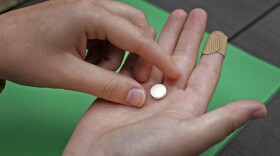 A woman prepares to take the first of two pills taken for a medical abortion during a visit to a Planned Parenthood clinic Wednesday, Oct. 12, 2022, in Kansas City, Kan. (Charlie Riedel/AP)