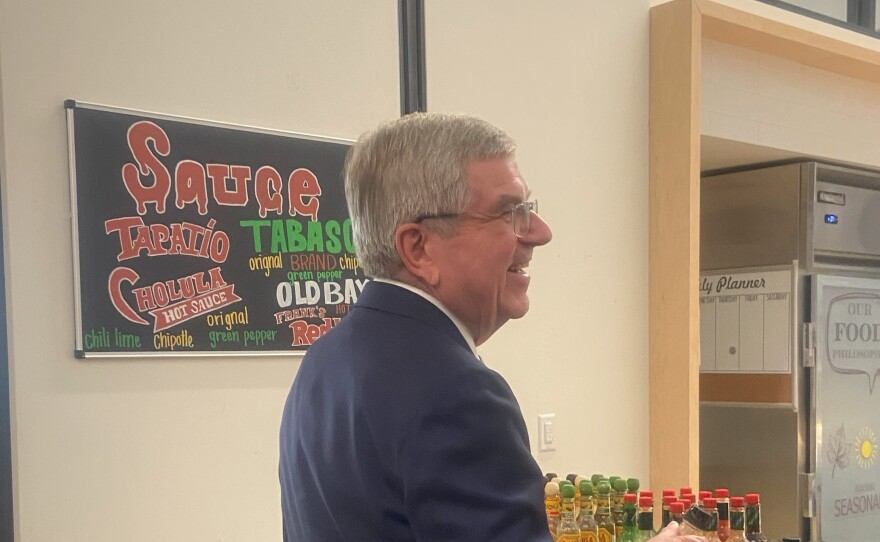 International Olympic Committee President Thomas Bach looks at hot sauce at the Kahlert Village dining hall at the University of Utah.