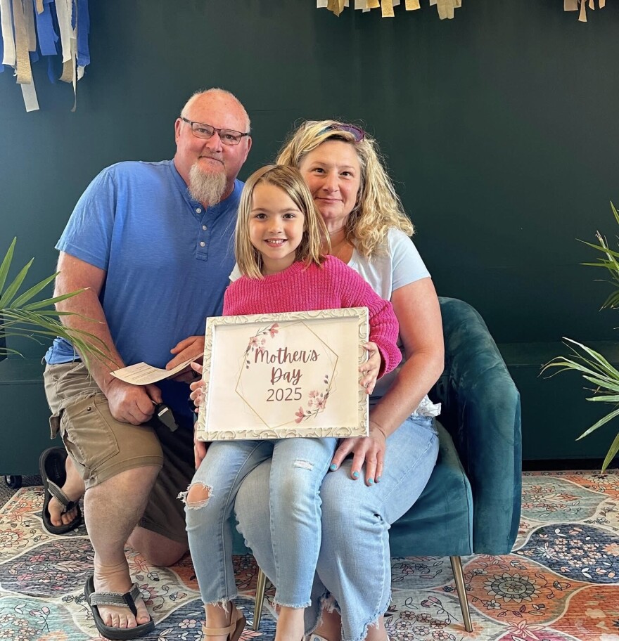 Toni Popham sits for a Mother's Dan portrait with her husband Scott and daughter