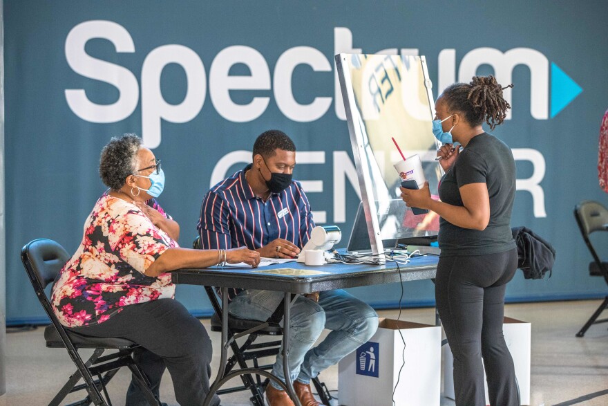 Poll workers assist a voter at the Spectrum Center, during the first day of early voting in Charlotte, North Carolina, on October 15, 2020.