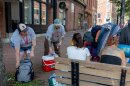 Lauren Chan, left, and Brandon Pratt, hand out water, snacks and electrolyte packs to two homeless women in Portland on July 16. Chan is program coordinator of the city's homelessness prevention and diversion program and Pratt is an outreach team member.