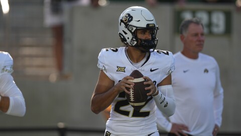 Colorado quarterback Dominiq Ponder, in a white jersey and helmet, holds a football