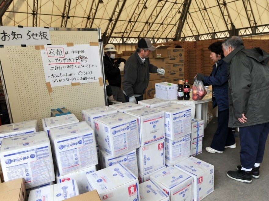 An elderly Japanese couple receives food and drinks from a distribution center in Kamaishi on Sunday.