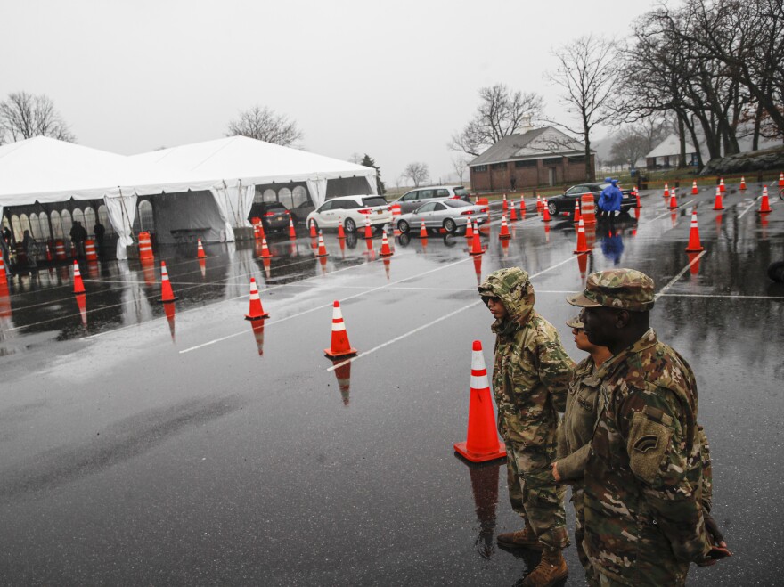 National Guard personnel stand beside a line of motorists waiting for COVID-19 coronavirus infection testing New Rochelle, N.Y., on Friday.