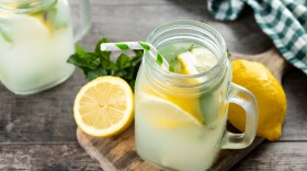 Lemonade drink in a jar glass and ingredients on wooden table