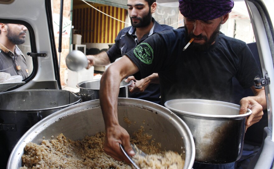 Rebels in the Free Syrian Army distribute food to fellow fighters in Aleppo on Wednesday.