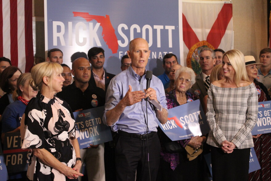 Governor Rick Scott, who is campaigning to replace U.S. Senator Bill Nelson, addressed his supporters Thursday alongside his wife Ann (left) and Attorney General Pam Bondi (right).