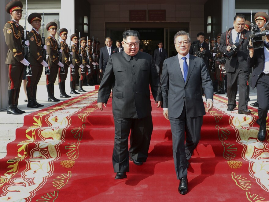 A photo provided by South Korea's Presidential Blue House shows North Korean leader Kim Jong Un, center left, and South Korean President Moon Jae-in, right, walking after their surprise meeting on Saturday in Panmunjom.