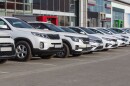  A row of new, white and grey cars line the lot at a dealership. 