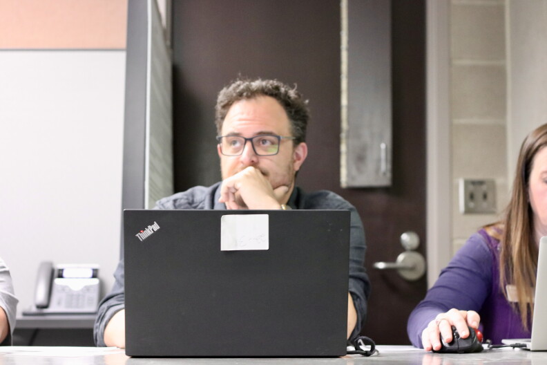Kyle Giddings sits behind a black laptop waiting to check people in to vote at the Jefferson County Jail.