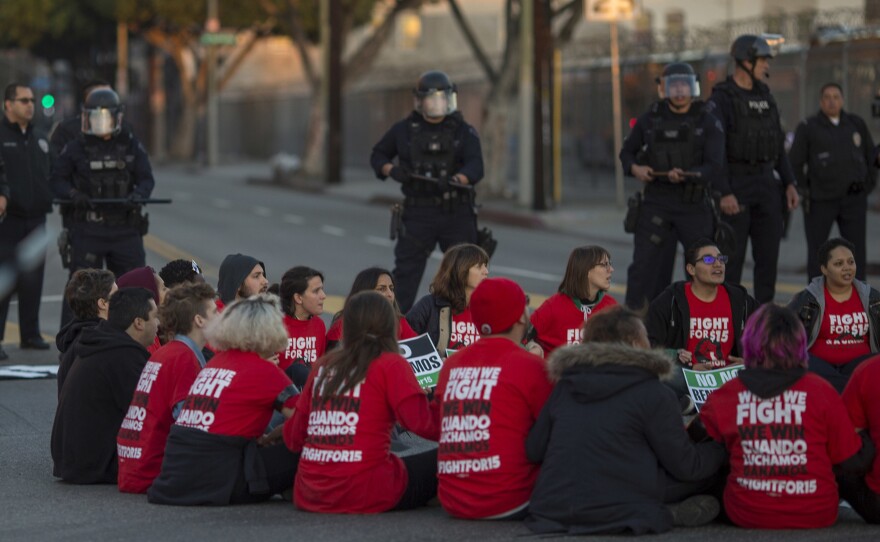 Police surround striking McDonald's workers sitting in an intersection in Los Angeles, demanding a $15 per hour wage and union rights during nationwide 'Fight for $15 Day of Disruption' in November 2016.