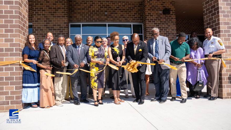 Alumni, staff and community members, including Superintendent John Gordon (center), cut the ribbon to commemorate the opening of the new John F. Kennedy Middle School in Suffolk on July 31, 2026.