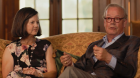 A man and a woman sitting on a gilded couch