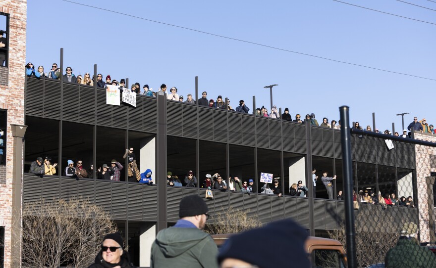 People line the edges of a parking garage to watch a rally. 