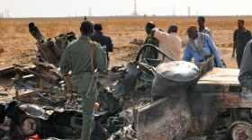 Sudanese troops stand next to a burnt-out military vehicle in the oil center of Heglig after clashes with South Sudanese forces Wednesday. Recent fighting has raised fears of a renewed war.