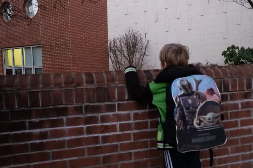 Leo Simmons peers over a wall at Lyman Elementary. Simmons, a student there, would be impacted by the plans for school closure.