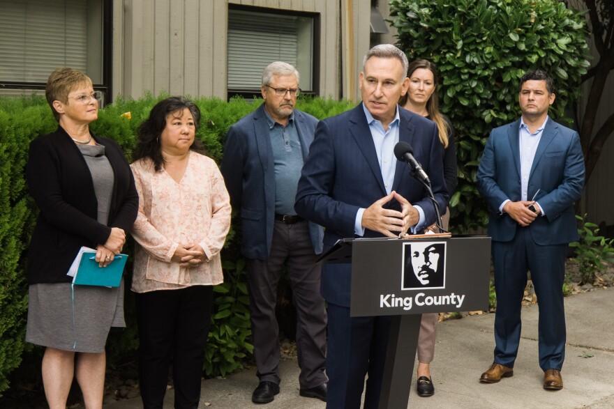 A group of people stand outside a building in North Seattle.  