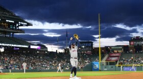 Several baseball players stand on the field of a large stadium